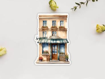 Preview: 8 Café Shop Sticker Set – Charmante kleine Cafés und Geschäfte Preview: Sticker mit der Fassade eines zweistöckigen Geschäftsgebäudes im mediterranen Stil, dekoriert mit Blumen in Fenstern und Pflanzen vor dem Eingang. Eine grüne Markise schützt den Eingang, vor dem ein Stuhl steht.